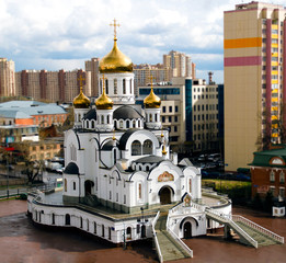 Obraz premium Beautiful white Christian Church with Golden domes on the background of the city landscape.