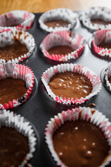 
A muffin baking dish in which there are paper inserts with chocolate dough inside. Homemade cakes for children and adults