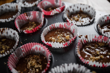 
A muffin baking dish in which there are paper inserts with chocolate dough inside. Homemade cakes for children and adults