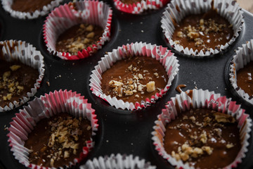 
A muffin baking dish in which there are paper inserts with chocolate dough inside. Homemade cakes for children and adults