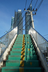 Stairs of overpass leading upward, with 2 skyscrapers and an electric pole exactly line up in the back.
