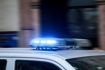 Fototapeta na wymiar Ein Polizeiauto mit Blaulicht fährt rasant vorbei.