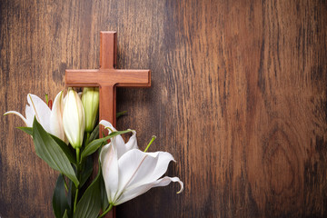 Wooden cross and white lily on rustic table