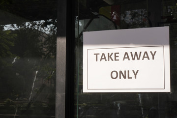 A paper notice sticking on window saying "TAKE HOME ONLY" during social distancing time.