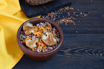 Buckwheat porridge with mushrooms in a ceramic bowl on a dark wooden rustic background