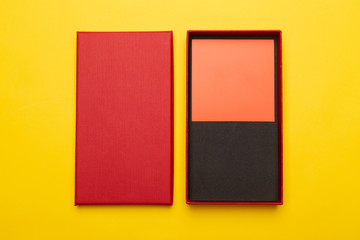 Red box product packaging with blank orange card isolated on yellow background. Flat lay.