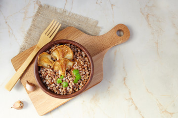 Buckwheat porridge with oyster mushrooms on a light background