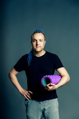 A portrait of a young man with an unusual hairstyle of mohawk from blue braids in sportswear....
