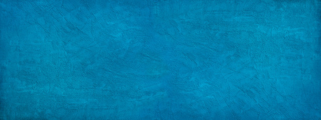 Beautiful abstract blue background. Texture of decorative plaster on a concrete wall. Bright blue banner with a rough grainy plastered surface.
