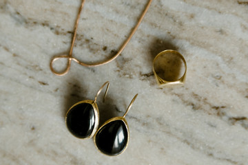 Obraz premium black pearl earrings jewelry in a gold frameand gold and silver rings on a marble table background