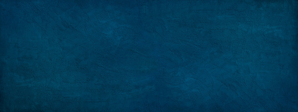 Dark blue background. Grunge blue background with copy space. Texture of decorative plaster on a concrete wall. A long banner with a blue texture of rough grained surface.