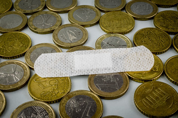 Sick economy. Concept for the economic disaster from the coronavirus pandemic. A band aid (medicated plaster) to fix euro currency coins.