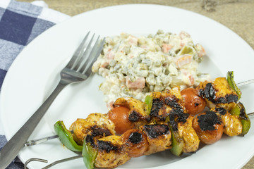 brochettes de poulet grillés dans un plat et légumes à la mayonnaise