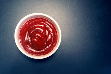 Tomato sauce in a white plate on a black background