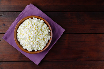 Cottage cheese on wooden boards. Fresh cottage cheese in a ceramic bowl. Clay plate with soft cheese on a linen napkin. Top view. Copy space