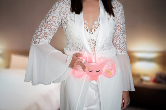 The cartoon of the uterus is on the woman's body on the bedroom background at night. A woman wearing satin white nightgown take unhealthy uterus illustration on the crotch. Health concept