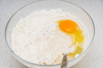 Preparation of the yeast dough. Dough with the egg`s yolk and flavour in the glass bowl is ready to be stirred.