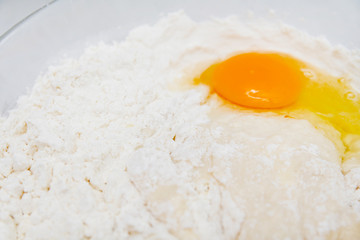 Preparation of the yeast dough. Dough with the egg`s yolk and flavour in the glass bowl is ready to be stirred.