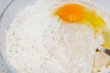 Preparation of the yeast dough. Dough with the egg`s yolk and flavour in the glass bowl is ready to be stirred.