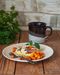 Light breakfast with cheesecakes and coffee, a bunch of mint on a wooden table