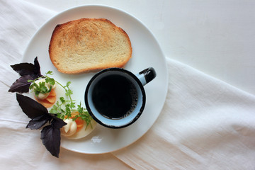 Hard boiled eggs cut in half, parsley, basil greenery, crispy white toast and cup of black coffee for healthy breakfast. White wooden background. Top view