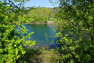 Ein Blick durch die Bäume auf den Kiesteich in Föhrste bei Alfeld an der Leine in Niedersachsen