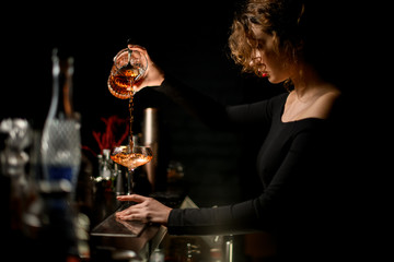 Beauty lady at bar masterfully pours drink into glass