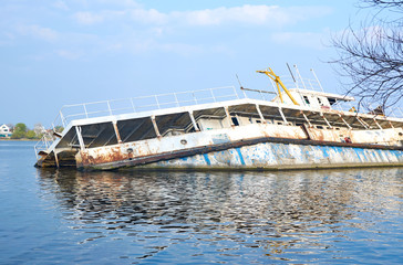Fototapeta na wymiar A sunken rusty ship half gone under the water of the sea, river, ocean.