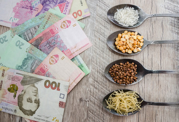 Fototapeta na wymiar composition with various types of legumes and cereals in spoons on a wooden table. Organic grains and dollars. The concept of economic crisis and rising prices. Rice, buckwheat, pasta and hryvnia.