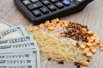 The concept of economic crisis and rising prices. buckwheat, rice, peas and pasta on a wooden background. Dollars and calculator. Close-up.