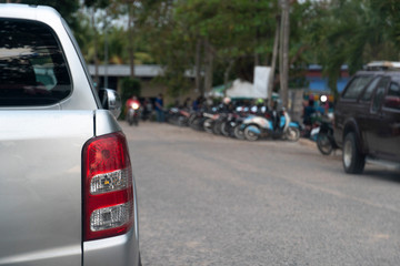 Naklejka premium Rear side of pickup car stop on asphalt road beside with blurred of cars parking arear and local market.