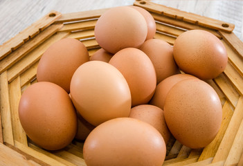 Chicken eggs in a wooden plate on a wooden table. Close-up.