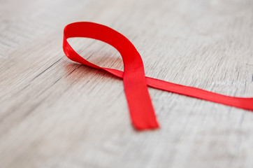 AIDS concept. Red ribbon on a wooden background.