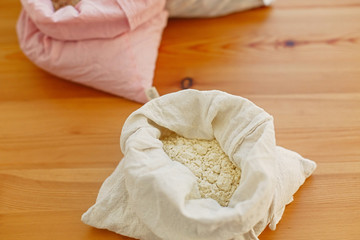 Organic corn flour in reusable bag close up. Groceries in reusable textile bags on wooden table. Plastic free delivery from bulk store. Zero waste shopping. Ban plastic