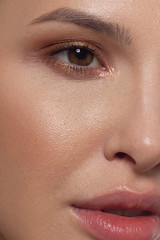 Naklejka premium Half a beauty portrait with beautiful fashionable evening make-up, black smoky eyes and extremely long eyelashes. Nude lipstick on the lips. Cosmetology and spa facial skin care