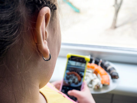 Girl photographing food served in sushi bar with mobile phone. Food concept