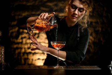 sexy female bartender gently pours drink into glass