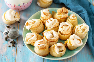Homemade cakes, cookies. Puff pastry cookie roll stuffed with icing sugar in a bowl on a wooden table.