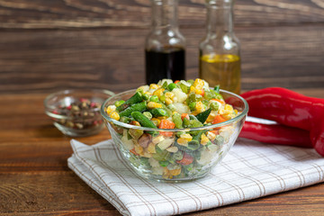 Frozen vegetables. Frozen vegetable mixture of carrots, corn and peas, celery and corn in a plate. Mexican mix. On a wooden background.