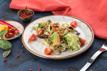 Fresh salad with chicken breast, lettuce and tomatoeson white plate on blue red background