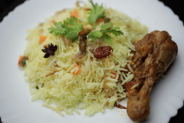 Chicken Biryani showing leg piece - It's a delicious recipe of Basmati rice mixed with with spicy marinated chicken in a bowl.  Served in a bowl or plate. Selective focus