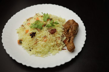Chicken Biryani showing leg piece - It's a delicious recipe of Basmati rice mixed with with spicy marinated chicken in a bowl.  Served in a bowl or plate. Selective focus