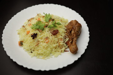 Chicken Biryani showing leg piece - It's a delicious recipe of Basmati rice mixed with with spicy marinated chicken in a bowl.  Served in a bowl or plate. Selective focus