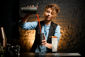 female bartender carefully pours tomato juice to metal cup