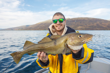 Happy fisherman with cod fish in hands