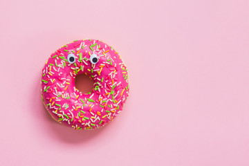 Pink donut with eyes on a pink background