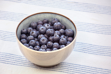Bowl with blueberry fruits on the kitchen table with tablecloth.