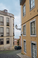 Fototapeta na wymiar Street with beautiful yellow buildings with lantern and brick road, Lisbon. Vertical shot