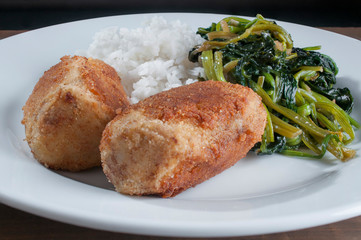 Close up  photography of Tuna Croquettes with steam rice and spinach on a white plate in a dark background
