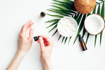 Female hands applying coconut oil for hand skin moisturizing. Flat lay composition with woman's...